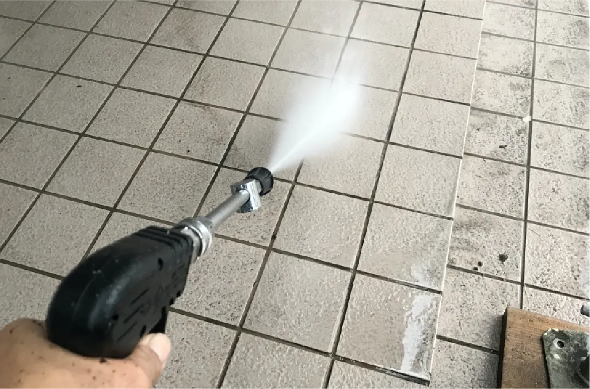 床面を高圧洗浄機で清掃している様子